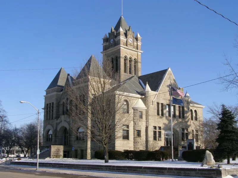 The Pulaski County Courthouse in Winamac, Indiana at golden hour, with the Tippecanoe River visible in the distance.